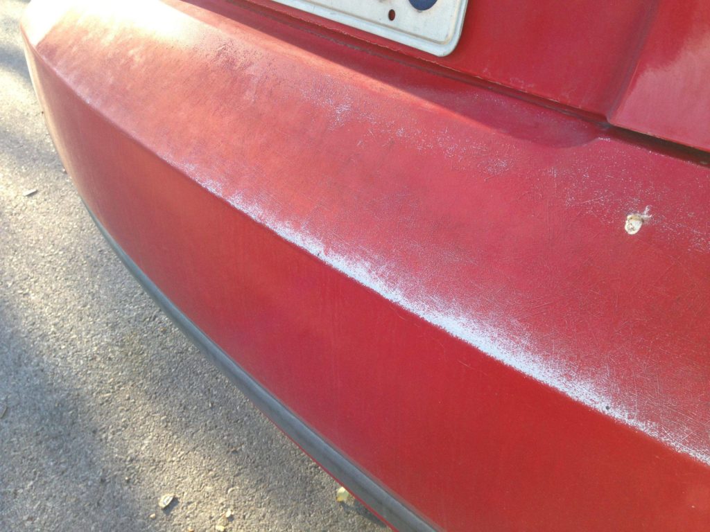 a faded line across a rear bumper of a red vehicle